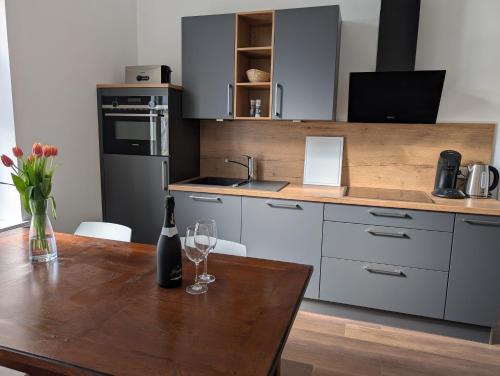 Winzervilla Kammerhof - 3x stilvolle & geräumige FeWos mit Moselblick, 2-12 Gäste buchbar, direkt am Moselradweg في برونبيبيرغ: مطبخ مع طاولة خشبية مع زجاجة من النبيذ