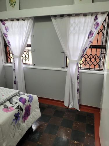 a bedroom with white curtains and a bed and a window at Transhaven Seaside Home in Durban