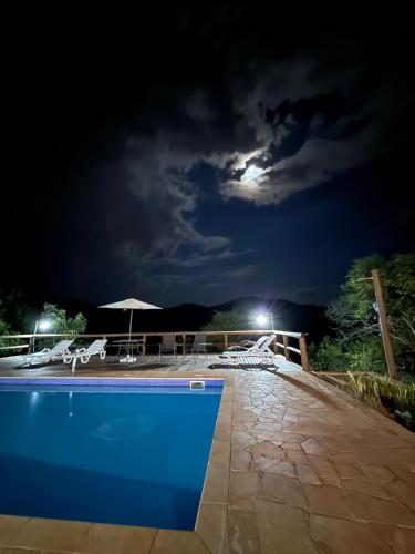 a pool at night with the moon in the sky at Chalé Canto da Mata - Com Piscina e Café da Manhã in Sapucaí-Mirim