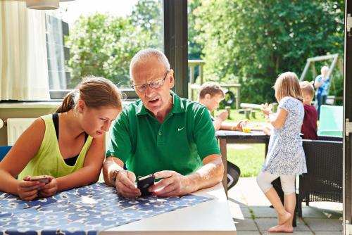 a man and a woman sitting at a table looking at a cell phone at Danhostel Viborg in Viborg