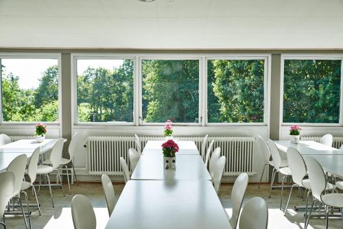 Habitación con mesas, sillas y ventanas blancas. en Danhostel Viborg, en Viborg