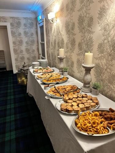 a long table with several plates of food on it at Crookston Hotel in Glasgow