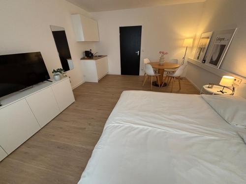 Un dormitorio con una cama blanca y una mesa. en Great Location Airport Exhibition Center Downtown, en Düsseldorf