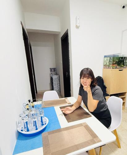 a woman sitting at a table with her hand on her mouth at Muscat Dormitory Male&Female in Muscat