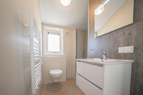 un bagno bianco con lavandino e WC di De IJssel Eilanden Chalet Casa Kampen mit Zaun Nr 548 a Kampen