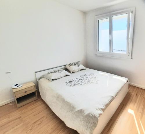 une chambre blanche avec un lit et une fenêtre dans l'établissement Appartement familial à 2 pas du lac, à Annecy