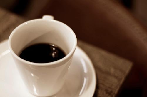 a cup of coffee sitting on a white plate at Pinestone Inn in Jian