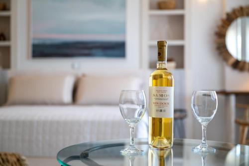 a bottle of wine sitting on a table with two wine glasses at Etesians Seaside House in Ágios Konstantínos