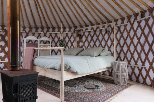 a bed in a yurt with a wood stove at Yurt Klyndobbe in Veenwoudsterwal