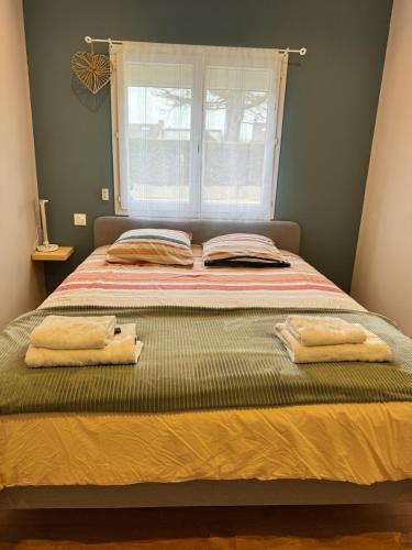 - un lit avec 2 serviettes et une fenêtre dans l'établissement Cottage Dolce vita à Bobital, à Bobital