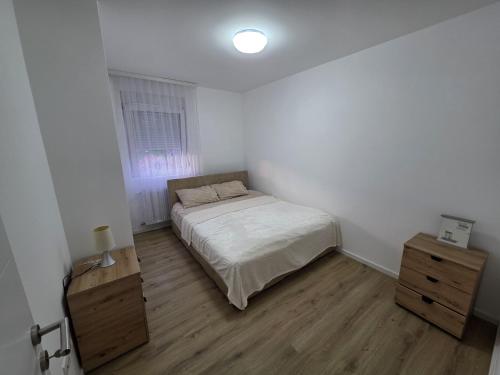 a white bedroom with a bed and a wooden floor at Varosmala in Novi Pazar