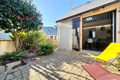 une chaise jaune assise à l'extérieur d'une maison dans l'établissement Maisonnette de charme Bord de mer Piscine, à Guidel