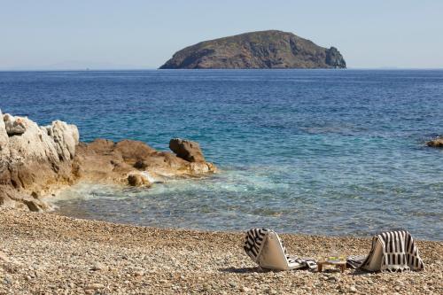 a pair of shoes on a rocky beach next to the ocean at Perma Serifos in Serifos Chora