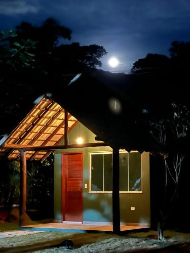 a small house with a red door at night at Chalé Sana-rio, seu conforto na serra! in Macaé