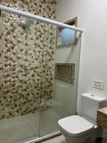 a bathroom with a toilet and a glass shower at Chalé Sana-rio, seu conforto na serra! in Macaé