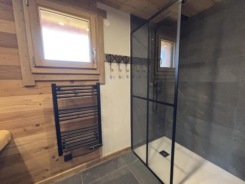 a glass shower in a bathroom with a window at Lumen Wood in La Bresse