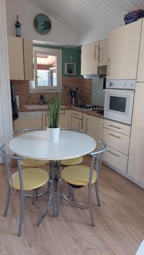 une cuisine avec une table blanche, des chaises et une table dans l'établissement Châlet en bois à 800m de la mer, à Sarzeau