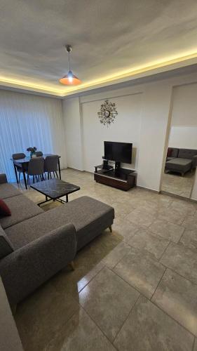 a living room with a couch and a flat screen tv at Turkuaz sitesi 2 odalı eşyalı ve havuzlu manzaralı kişi fiyatı değil oda fiyatı in Side