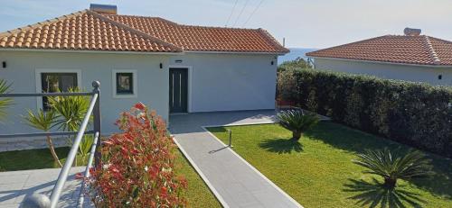 a white house with a garden and a fence at Vista Blu Villa in Vlachata