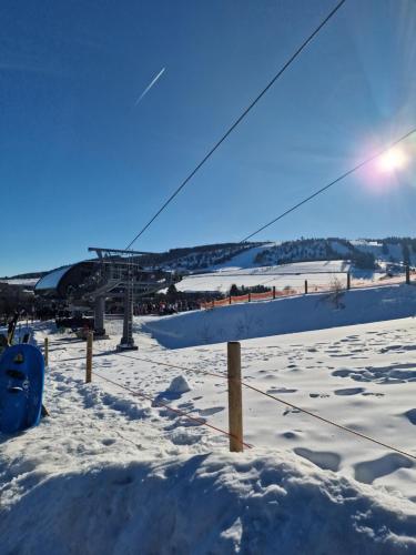 a snow covered field with a bridge in the background at WillingenHOME in Willingen