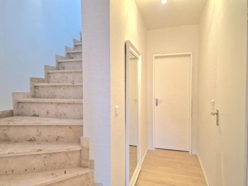 a hallway with stairs and a white door at WillingenHOME in Willingen