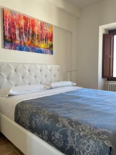 a bed in a bedroom with a painting on the wall at Le Finestre sul Duomo in LʼAquila