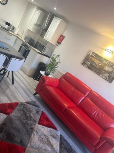 a red couch in a living room with a kitchen at 4 star Rating 2 bed Newly renovated city apartment with free parking in Belfast