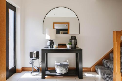 a black console table with a mirror on a wall at Tobela House, Sleeps 10, Ultra Luxury in Lambeg