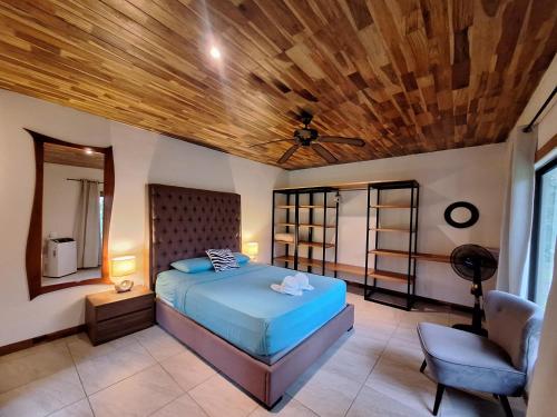 a bedroom with a blue bed and a chair at Corcovado Accommodations-pool-best views-nature in Puerto Jiménez