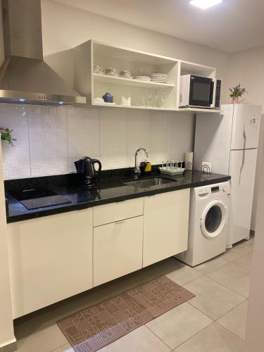 a kitchen with white cabinets and a washer and dryer at Apartamento completamente equipado! in Encarnación