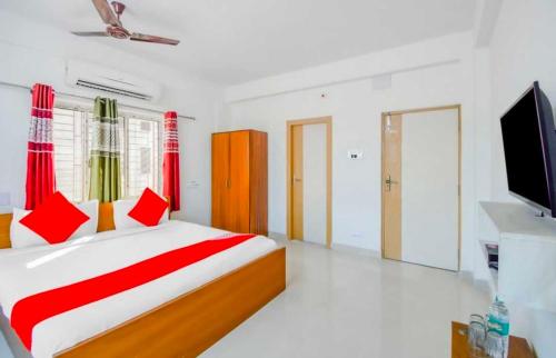 a bedroom with a bed with red pillows and a television at Hotel O Amar Raj Stay in Kolkata