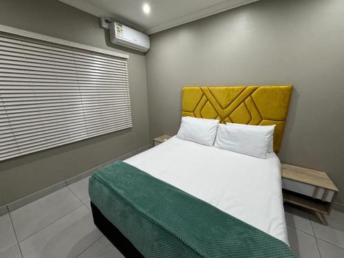a bedroom with a large bed with a yellow headboard at Durban Holiday Apartments by Mieli Estates , Unit 6 in Durban