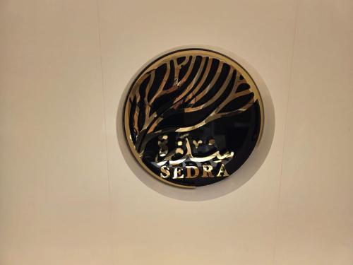 a black and gold sign on a wall at Sedra Global Hotel, Madinah - فندق سدرة العالمى, المدينة in Al Madinah