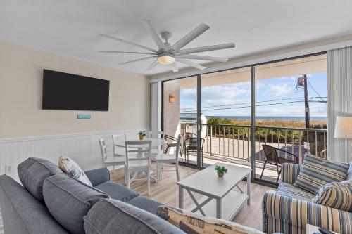 a living room with a couch and a tv and a balcony at Paradise Towers #104 in Carolina Beach