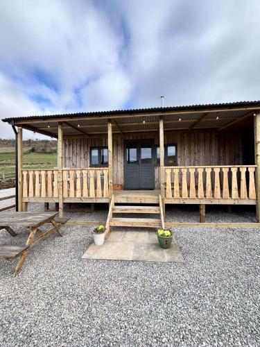 a wooden cabin with a porch and two potted plants at Dark Skies den in Fryup