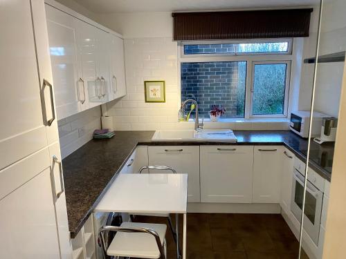 a kitchen with white cabinets and a sink and a window at The Premier Living Experience Entire 2-Bedroom Modern Apartment in Bromley