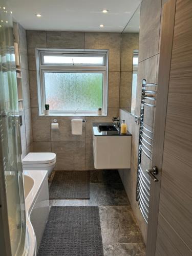 a bathroom with a sink and a toilet and a window at The Premier Living Experience Entire 2-Bedroom Modern Apartment in Bromley
