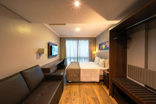 a hotel room with a bed and a couch at Prodigy Gramado by Wish in Gramado