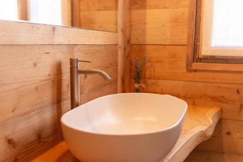 a bathroom with a white sink on a wooden wall at Agri Alloggio La Quercia e il Frassino in Fino del Monte