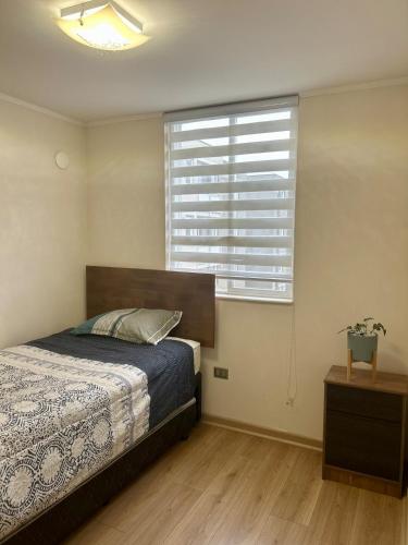 a bedroom with a bed and a large window at Amplio departamento in Temuco