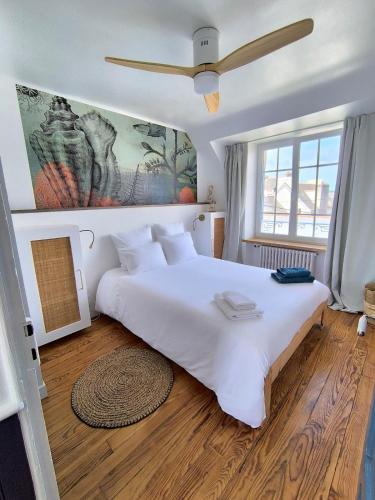 une chambre avec un grand lit blanc et une fenêtre dans l'établissement Au calme, maison en pierres proche de la plage, au Guilvinec