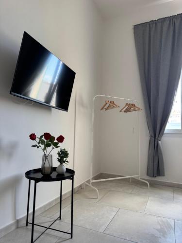 a room with a table with a tv on the wall at L&S Rooms in Monopoli