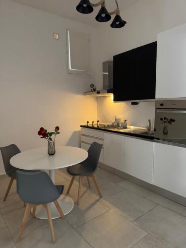 a kitchen with a white table and chairs and a table and a counter at L&S Rooms in Monopoli