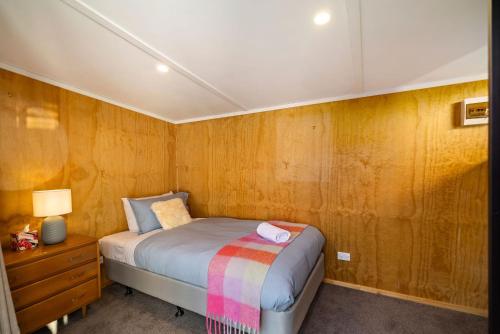 a bedroom with a bed and a wooden wall at Arrowtown Family Home with spa in Arrowtown