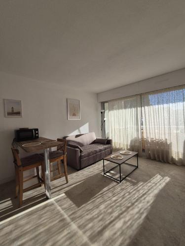 un salon avec un canapé et une table dans l'établissement Charmant studio Climatisé avec Terrasse, Piscine et Parking dans le beau quartier du PONANT, à La Grande Motte
