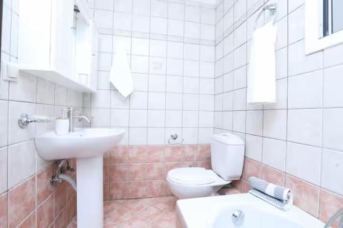 a white bathroom with a toilet and a sink at Maison See View in Kontokali