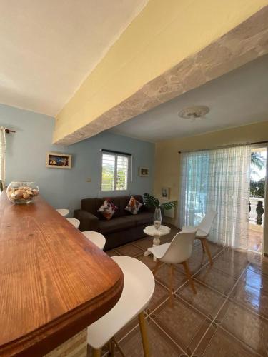 a living room with a wooden table and white chairs at El Castillo Tropical in Cabrera
