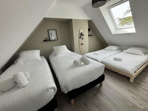 une chambre avec trois lits et une fenêtre dans l'établissement la maison du bord de mer, à Penvénan