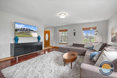 Chic Lake Geneva Retreat Spring & Summer Getaway Near Lake & Golf في بحيرة جنيف: غرفة معيشة مع أريكة وتلفزيون بشاشة مسطحة