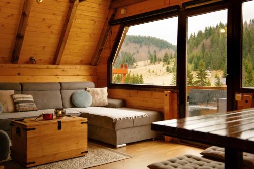 a living room with a couch and a large window at Owl House Jelovica in Berane